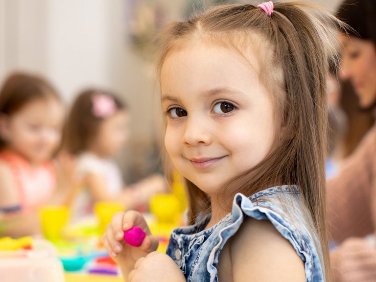 Kindergruppe knetet - ein kleines Mädchen blickt in die Kamera