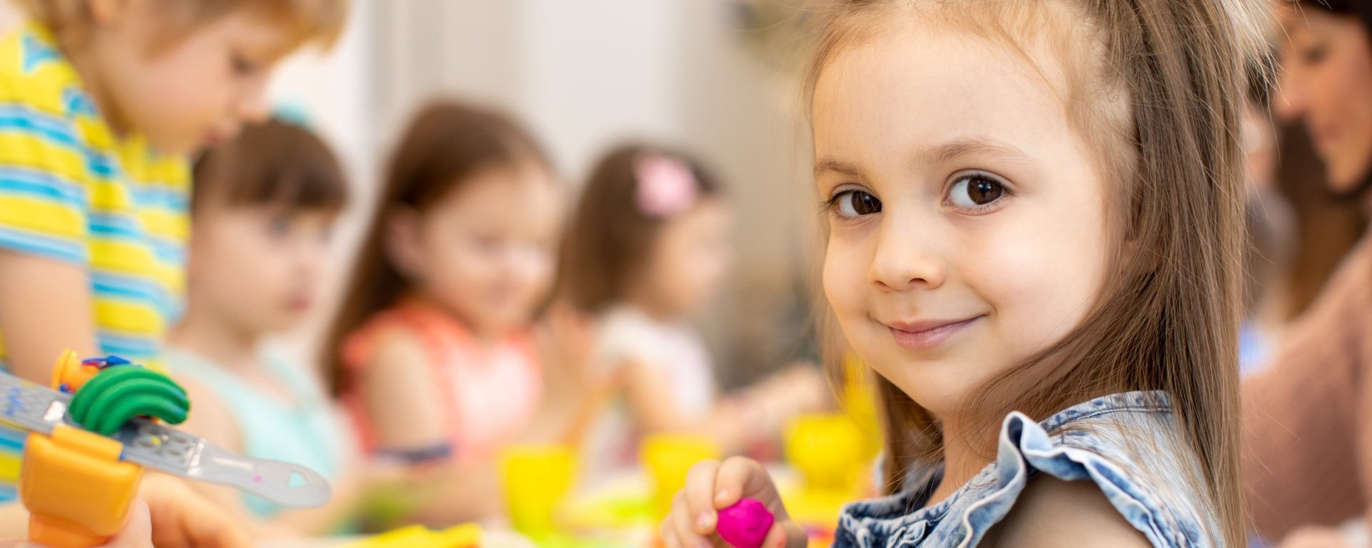 Kindergruppe knetet - ein kleines Mädchen blickt in die Kamera